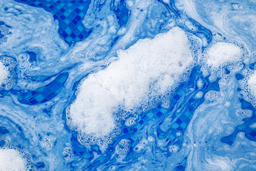 Soap foam on the water in the pool as an abstract background. Blur