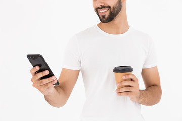 Image cropped of handsome joyful man drinking coffee takeaway and using cellphone