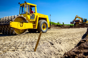 Road roller with spikes is working at construction site