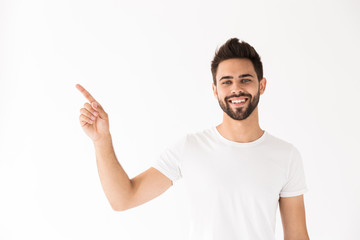 Image of attractive smiling man looking at camera and pointing finger aside at copyspace
