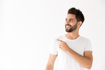 Image of happy young man smiling and pointing finger aside at copyspace