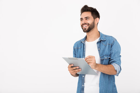 Image of handsome cheerful man holding clipboard and writing while smiling