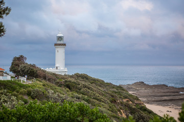 Fototapeta na wymiar Lighthouse overlooking the sea with dark skies overhead.
