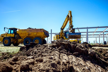 Backhoe is loading a truck with ground on building site