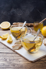 Two cups of natural herbal tea ginger lemon and honey on a wooden background. Copy space