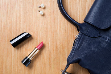 lipstick and black round bag on wood table