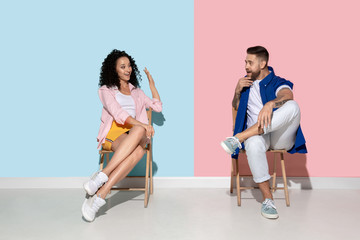 Obraz premium Young emotional man and woman in bright casual clothes posing on pink and blue background. Concept of human emotions, facial expession, ad. Beautiful caucasian couple looks astonished, shocked.