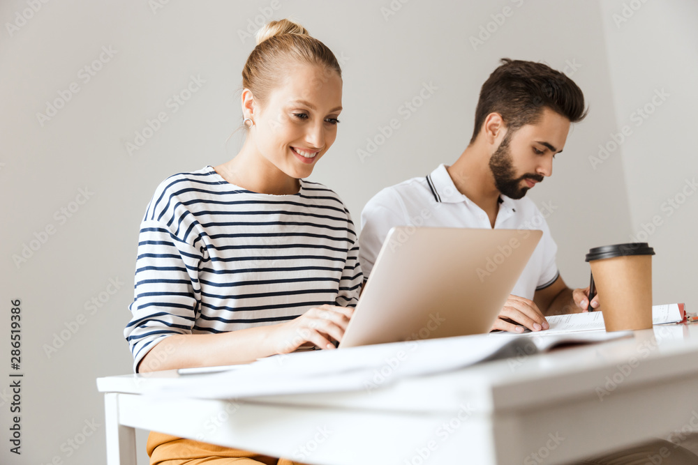 Poster cheerful loving couple friends man and woman sitting at the table indoors using laptop computer writ