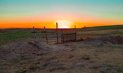 Old gate in the steppe on the background of the sunrise. Landscape. The day will be hot.
