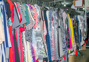 Buyers choose clothes. Female clothes on hangers and shelves in a clothing store. Casual clothes for girls and children. Fashionable style. Boutique in the mall. Discounts and sale.