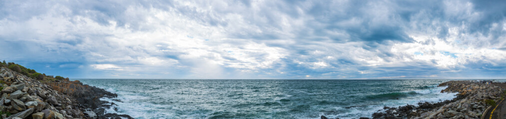 Fototapeta na wymiar Panoramic view of ominous cloud formations on the coast.