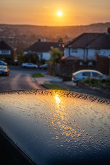 Dawn sun reflected in a dew covered car roof