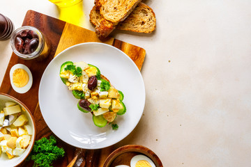 Open sandwich with traditional German potato salad, bread, all ingredients on pale pink background, top view