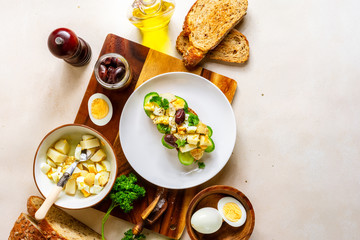 Open sandwich with traditional German potato salad, bread, all ingredients on pale pink background, top view