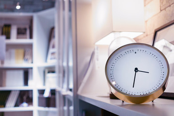 Modern alarm clock in home library and living room with blurred bookshelf background at night time.