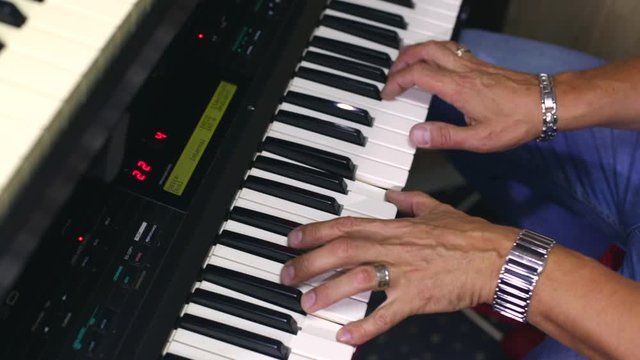 A man plays the synthesizer. Musician playing electric piano hands close-up. View from above