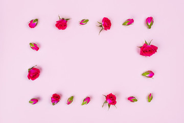Beautiful roses on pink background, top view.