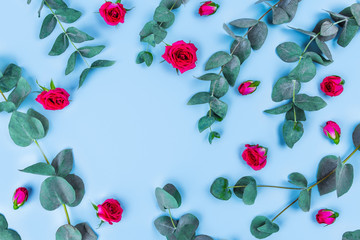 Beautiful sprigs of eucalyptus and roses on blue background, top view.