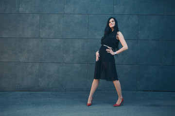 Fototapeta premium a beautiful brunette in a black dress and red shoes. Woman advertises accessories, clothes, shoes