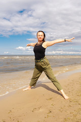 Obraz premium A woman practices yoga by the sea or ocean. Healthy lifestyle and health care. Outdoor sports.