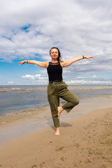 Obraz premium A woman practices yoga by the sea or ocean. Healthy lifestyle and health care. Outdoor sports.