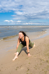 Fototapeta na wymiar A woman practices yoga by the sea or ocean. Healthy lifestyle and health care. Outdoor sports.