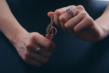 Golden violin key in the hands of women. jewellery: brooch and rings