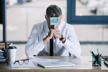 businessman in suit sitting with sticky note on forehead