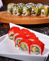 Sushi set compositionally located on a dark surface.