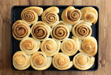 Twisted buns made from yeast dough with cinnamon, cane sugar and coconut flakes on a brown background