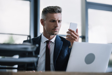 Fototapeta premium selective focus of businessman looking at smartphone in office