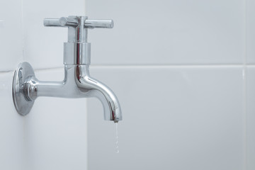 Silver metal faucet on white tile floor