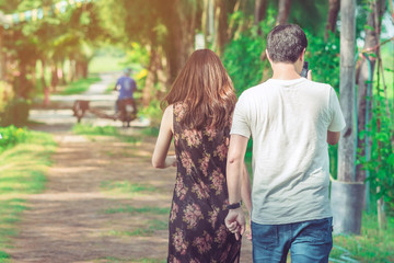 Naklejka premium Couple walking and taking photos under the pine trees in the public park.