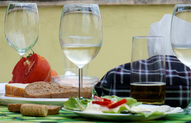 Glasses of white wine at a casual dinner setting with tomato, salad and bread.