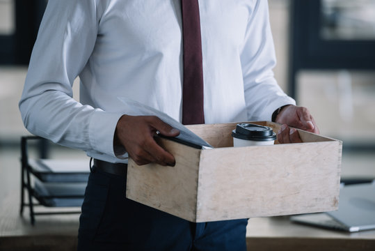 cropped view of dismissed man holding wooden box in office