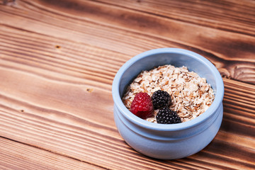 Blue pot of cereal with fresh berries on a wooden table