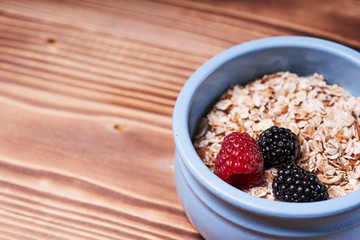 Blue pot of cereal with fresh berries on a wooden table
