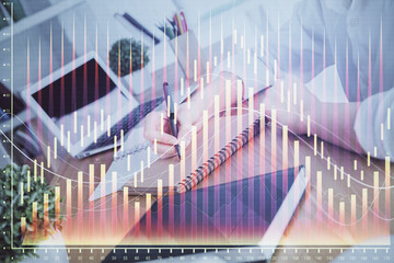 Financial graph displayed on woman's hand taking notes background. Concept of research. Double exposure