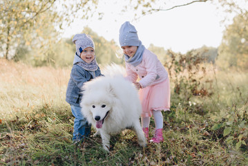 little girl and boy in autumn on nature with a dog