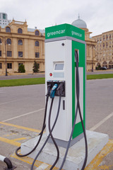 The panel with two pistols for charging electric vehicles close-up. Electric charge station for eco car with charger to recharge electricity into vehicle on city street outdoor .