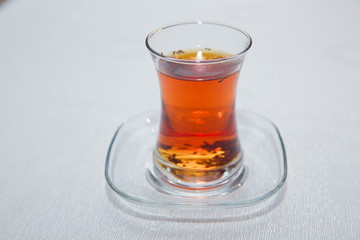 Tea in Azerbaijani traditional armudu pear-shaped glass . Azerbaijan black tea with vintage white table . Black turkish tea in pear shape glass, traditional Azerbaijani aromatic tea in armudu cup .
