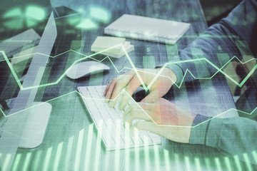 Stock graph with businessman typing on computer in office on background. Concept of analysis. Double exposure.