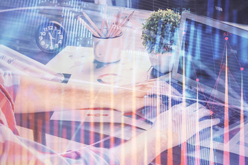 Double exposure of stock graph with businessman typing on computer in office on background. Concept of hard work.