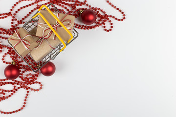 Naklejka premium Gifts in a small shopping basket on a white background with Christmas decorations, concept, copy space.