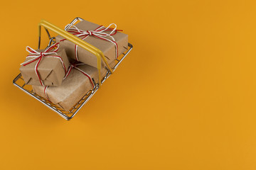 Gifts in a small shopping basket on a yellow background, concept, copy space.