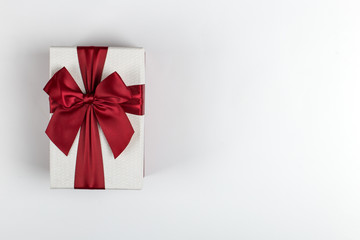 Gift with a red ribbon and a bow on a white background, copy space.