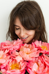 Fototapeta premium Beautiful girl is happy with flowers on her birthday, face of a girl close up with peonies, valentine's day