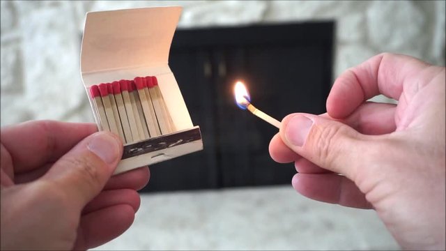 person lighting match for fireplace