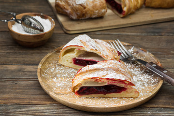 Strudel with cherry on wooden background. Rustic style