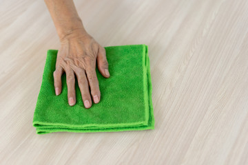 close up maid house keeper using microfiber fabric swipe on wooden table to cleaning after finished cooking